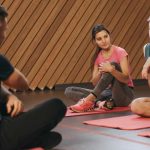 Active yoga class with adults on mats in a modern indoor setting.