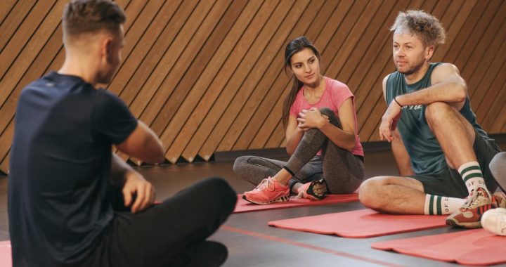 Active yoga class with adults on mats in a modern indoor setting.